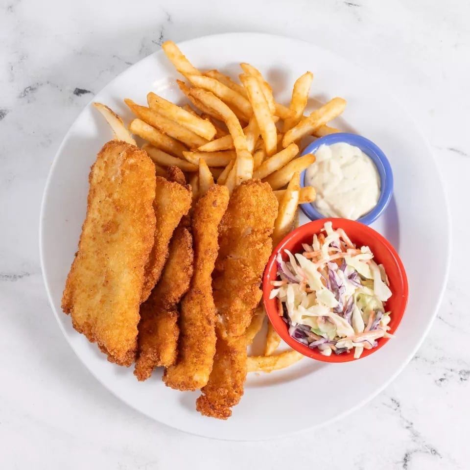 Crispy fried fish fillets and golden french fries with coleslaw and tartar sauce on a white plate.