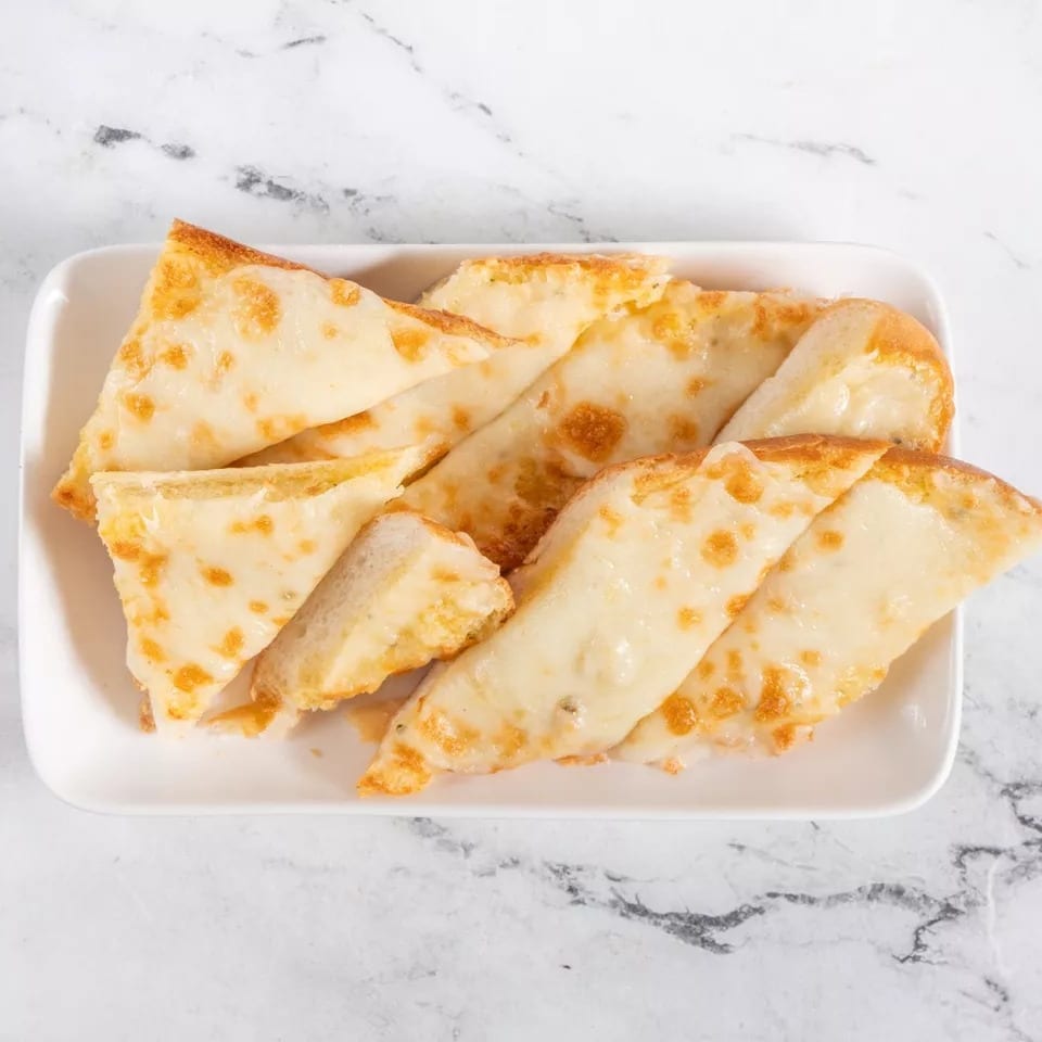 A white rectangular plate filled with golden-brown cheesy garlic bread slices on a marble surface.